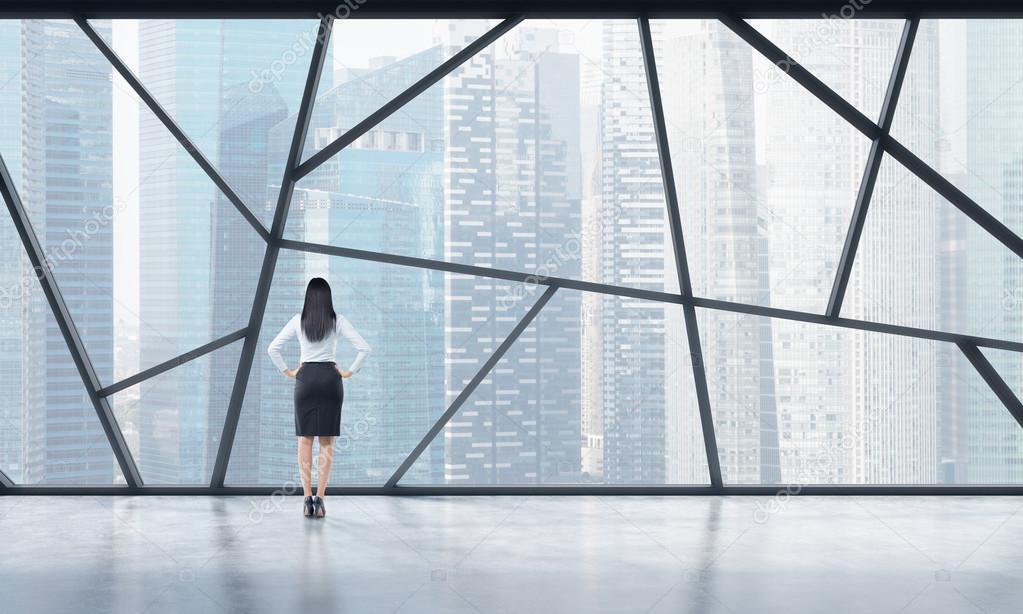 Rear view of a full length lady in formal clothes who is looking out the window in a modern panoramic open space in Singapore. The concept of highly professional financial or legal services.