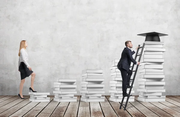 A woman is going up using a stairs which are made of white books to reach graduation hat while a man has found a shortcut to get education. Concrete wall and wooden floor. — Stock Photo, Image