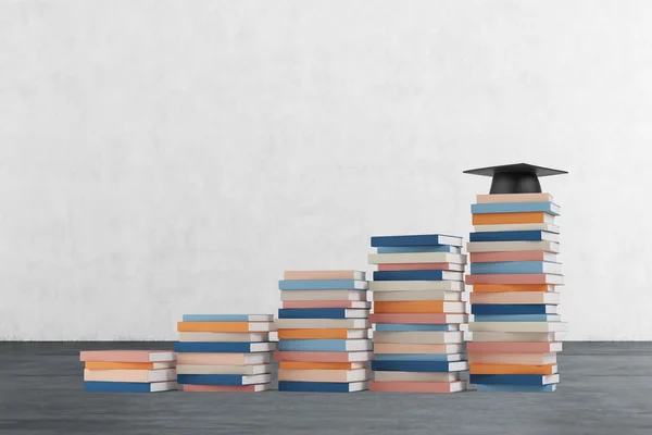 Un escalier est fait de livres colorés. Un chapeau de graduation est sur la dernière étape. Mur en béton et plancher en bois . — Photo