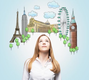A beautiful woman is looking up by dreaming about the visiting of the most famous places in the world. The concept of tourism and sightseeing. Light blue background.