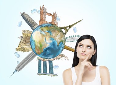 A brunette woman thinks about travelling. A globe with sketched famous places. Light blue background. Elements of this image furnished by NASA.