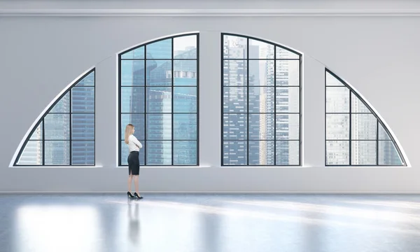 Rear view of a woman in formal clothes who is looking out the window in a modern loft interior. Singapore city view. — Stok fotoğraf