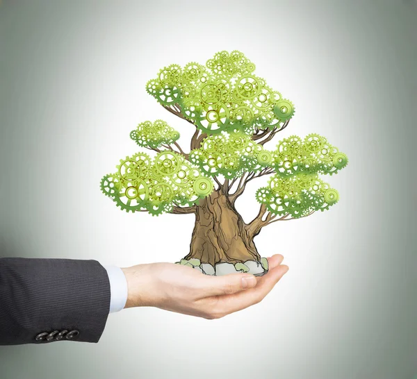 A hand in formal suit holds a sketched tree on the palm. Light grey background. A concept of the process of a growing business or a start up. — Stock fotografie