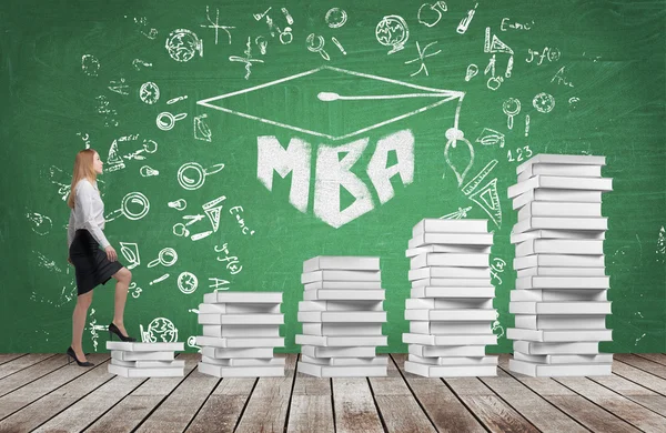 A woman is going up using a stairs which are made of white books to reach graduation hat. The written word MBA is drawn on the green chalkboard which symbolises a professional business education. — Stock Photo, Image