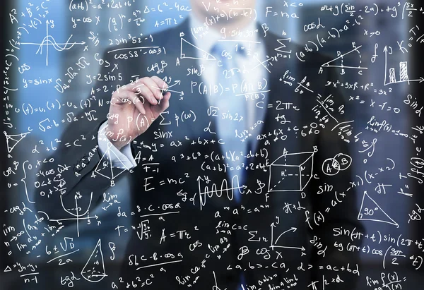 Un uomo d'affari sta scrivendo formule matematiche sullo schermo di vetro nel moderno ufficio panoramico serale. . — Foto Stock