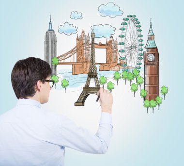 A handsome young man is drawing a colourful sketches of the most popular cities in the world. The concept of travelling. London, Singapore, Pisa, Paris. Light blue background.