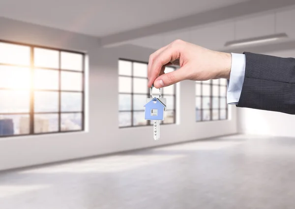 Un hombre con traje formal tiene una llave en un apartamento o oficina panorámica loft moderno. Alquile o compre una casa u oficina nueva. Vista de Nueva York. Una puesta de sol . — Foto de Stock