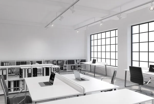 Workplaces in a bright modern loft open space office. Tables equipped with laptops; corporate documents' shelves. White copy space in the panoramic windows. 3D rendering. — 스톡 사진