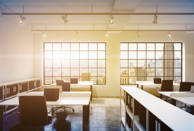 Workplaces in a bright modern loft open space office. Tables equipped with laptops; corporate documents' shelves. New York in the panoramic windows. 3D rendering. Toned image.