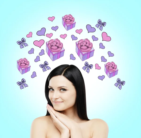 A brunette beautiful woman is dreaming about the gift. Purple gift and heart icons are drawn on the light blue background. — Stok fotoğraf