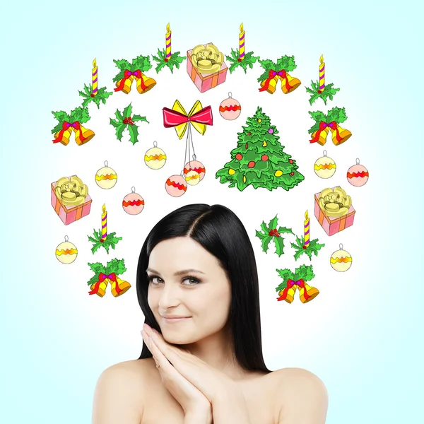 A portrait of a smiling brunette who is waiting for Christmas and New Year's Eve. Christmas-tree decorations are drawn on the light blue background. — Zdjęcie stockowe