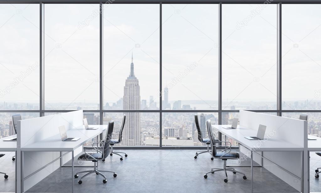 Workplaces in a bright modern open space office. White tables equipped with  modern laptops and black chairs. New York in the panoramic windows. 3D  rendering. Stock Photo by ©denisismagilov 90053362