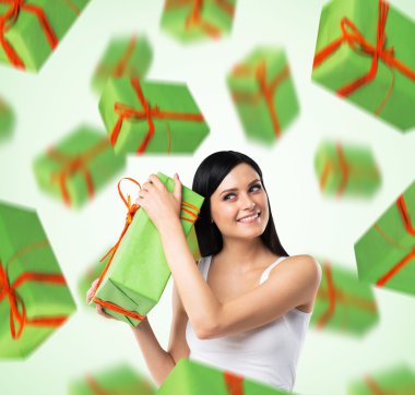 A portrait of dreaming woman who imagines green gift boxes. Light green background.