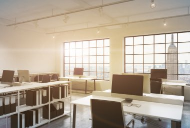 Workplaces in a sunset loft open space office. Tables are equipped with computers; book shelves. New York panoramic view. A concept of a high quality consulting services. Toned image. 3D rendering.