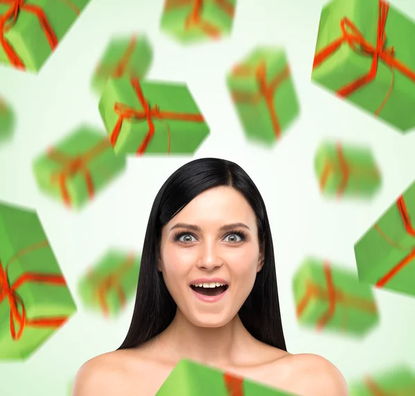 A portrait of astonishing woman who imagines green gift boxes. Light green background. — Stock Photo, Image