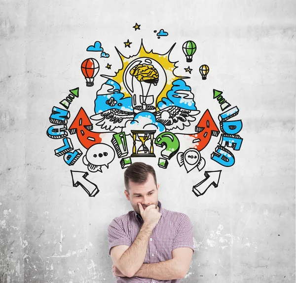 A handsome young man in casual clothes is forecasting a building of a business plan for business development. A colourful business plan sketch is drawn on the concrete wall behind the person. — 图库照片