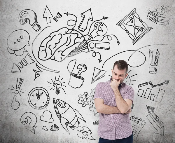 A handsome young man in casual clothes is thinking about business development. A brainstorm sketch is drawn on the concrete wall. — Stockfoto