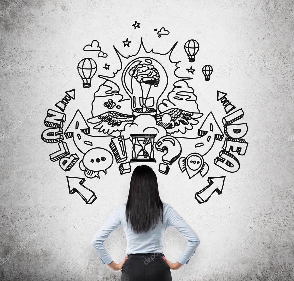 A rear view of a brunette business lady who is looking at the concrete wall with the drawn sketch about business ideas and development of business plan.