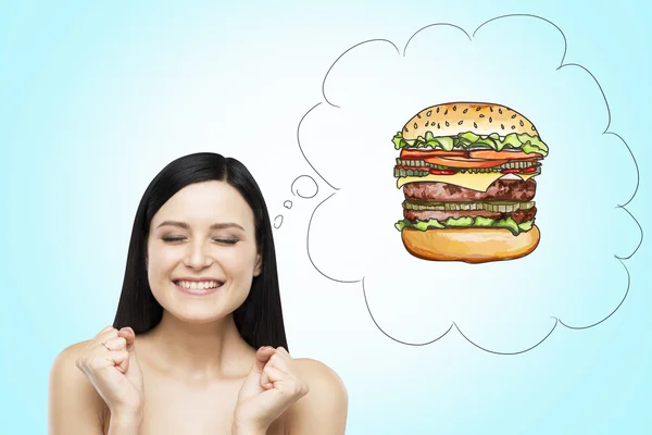 A brunette woman is thinking about burger. A fast food concept. Blue background. — Stock Fotó