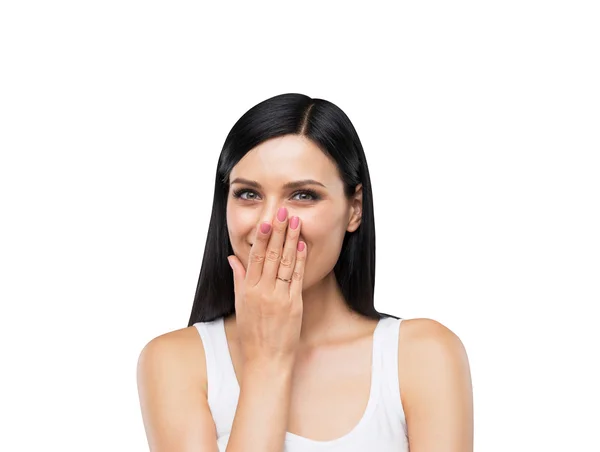 Un retrato de una morena feliz con una camiseta blanca que se cubre la boca de la mano. Aislado sobre blanco . —  Fotos de Stock