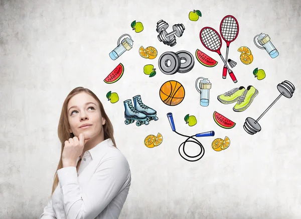 Soñar hermosa dama está pensando en su elección de la actividad deportiva. Iconos deportivos de colores se dibujan en la pared de hormigón. Un concepto de un estilo de vida saludable . — Foto de Stock