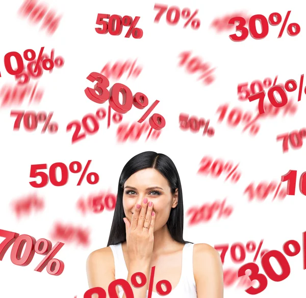 A portrait of a happy brunette lady in a white tank top who is dreaming about discounts. Red percentage marks are flying around the lady on white background. — Stock Photo, Image