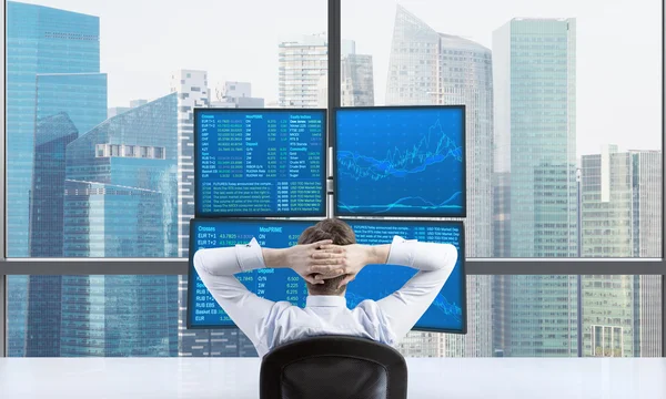 Rear view of a relaxing trader who is sitting in front of a trading station which consists of four screens with financial data. A concept of forex trading. Singapore panoramic view. — Stock Photo, Image