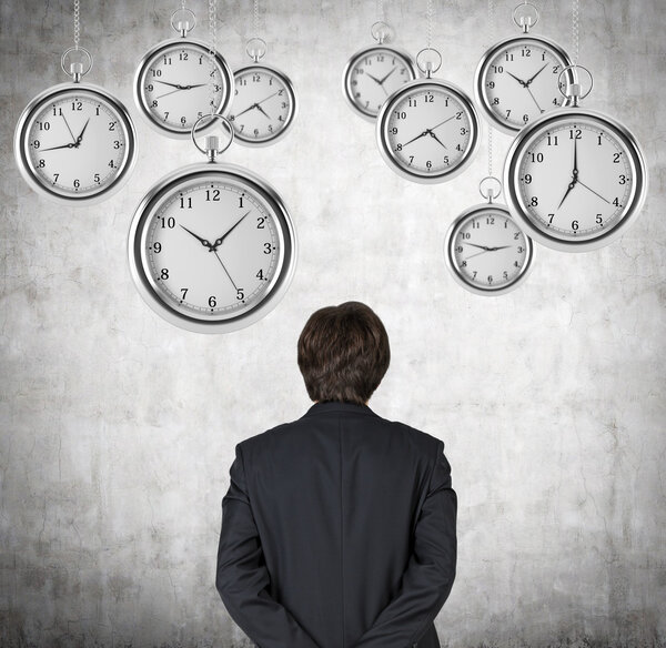 Вид сзади на бизнесмена, который смотрит на висящие в воздухе карманные часы. Концепция ценности времени в бизнесе. Конкретный фон
.