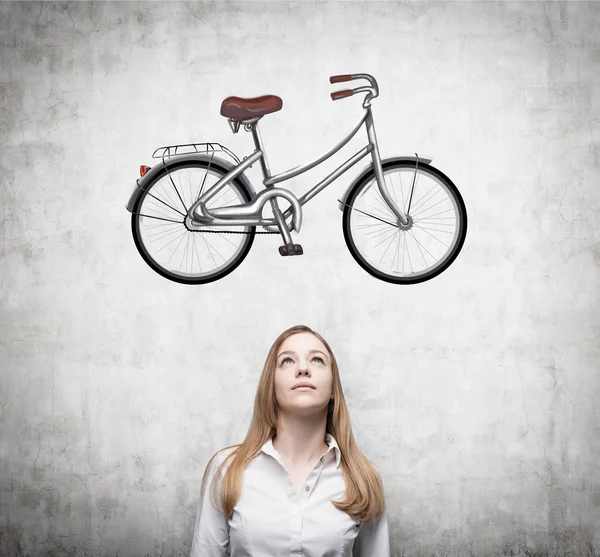 Seorang gadis cantik berpakaian formal bermimpi tentang sepeda baru. Sketsa sepeda digambar di dinding beton . — Stok Foto