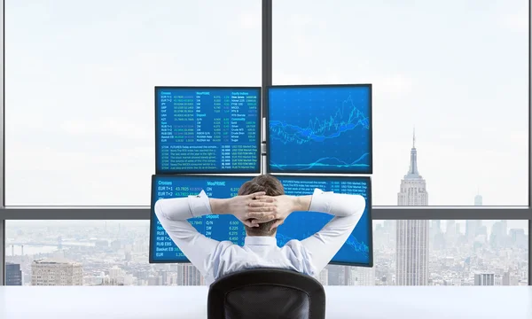 Vista trasera de un comerciante relajante que está sentado frente a una estación de comercio que consta de cuatro pantallas con datos financieros. Un concepto de comercio de divisas. Vista panorámica de Nueva York . —  Fotos de Stock