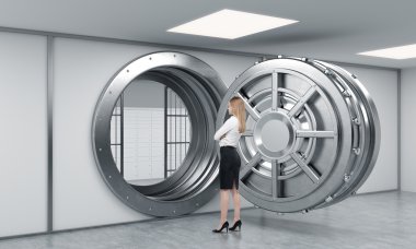 young lady standing in front of a big unlocked round metal safe 