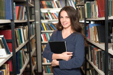 smiling young lady with long dark hair standing and holding a bl