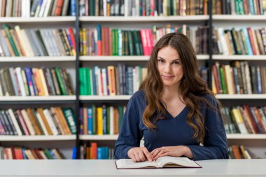 smiling young girl with loose long dark hair  sitting at a desk 