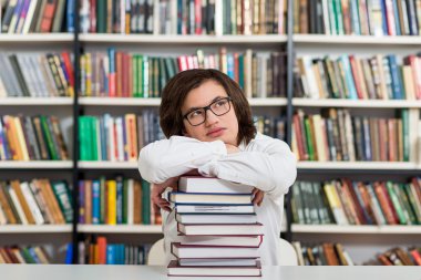 young man sitting at a desk in the library with his arms on a bi