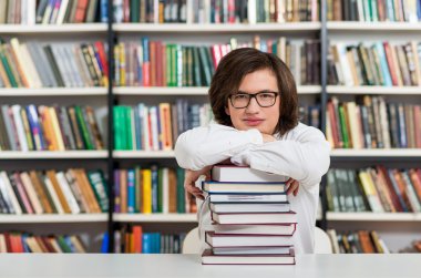 smiling young man  sitting at a desk in the library with his arm