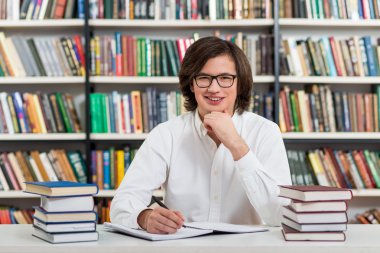 smiling young man with dark hair  sitting at a desk in the libra