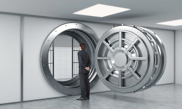 Young man standing in front of a big unlocked round metal safe i — 스톡 사진