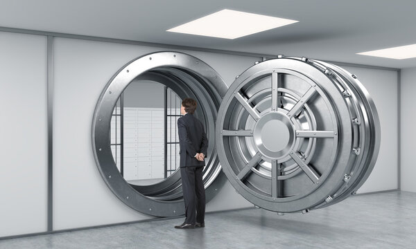 young man standing in front of a big unlocked round metal safe i