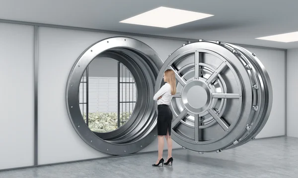 Young lady standing in front of a big unlocked round metal safe — Φωτογραφία Αρχείου