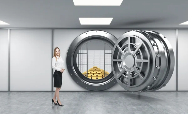 Young lady standing in front of a big unlocked round metal safe — 스톡 사진