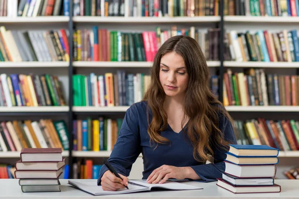 Serious young girl with loose long dark hair sitting at a desk i — Stockfoto