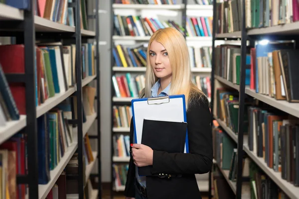 Young lady with blond hair standing and holding a black copy boo — 스톡 사진
