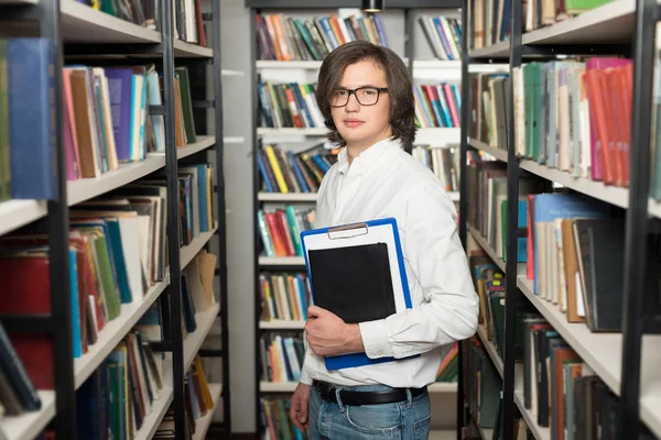 Joven con el pelo oscuro de pie y sosteniendo un libro negro — Foto de Stock