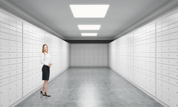 A beautiful private manger of a bank is standing in a room with safe deposit boxes. A concept of storing of important documents or valuables in a safe and secure environment. — Stockfoto