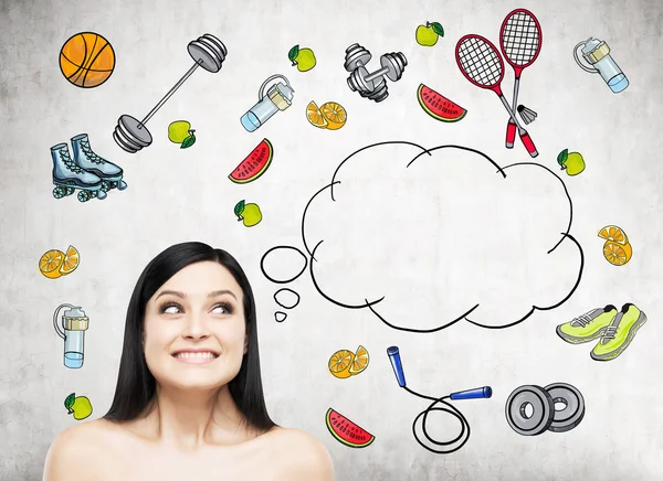 Dreaming beautiful lady is thinking about her choice of sport activity. Colourful sport icons are drawn on the concrete wall. A concept of a healthy lifestyle. — Stock Photo, Image