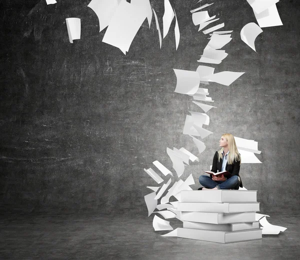 Frau sitzt auf einem Stapel Bücher und denkt über Problem nach — Stockfoto