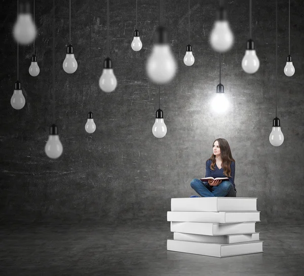 Woman sitting on a pile of books thinking about problem — Stockfoto