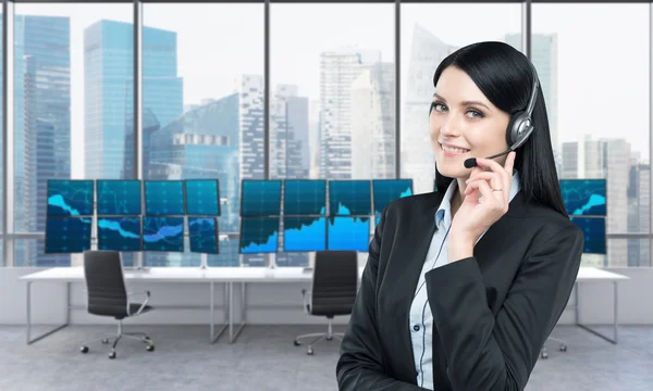 Woman in headphones in front of screens with trading data — Stock Photo, Image