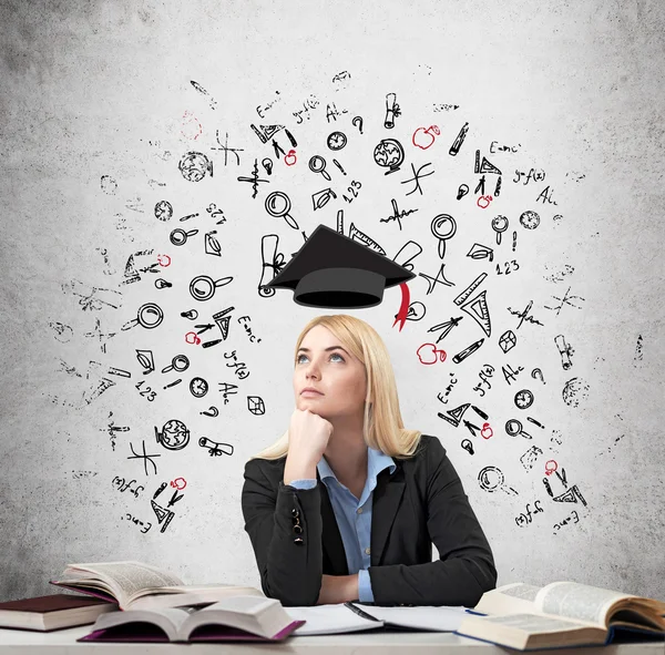 Femme assise au bureau avec des livres autour de la pensée éducation — Photo