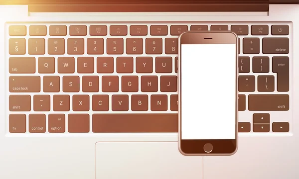 Smartphone on laptop keyboard, workplace — Stockfoto